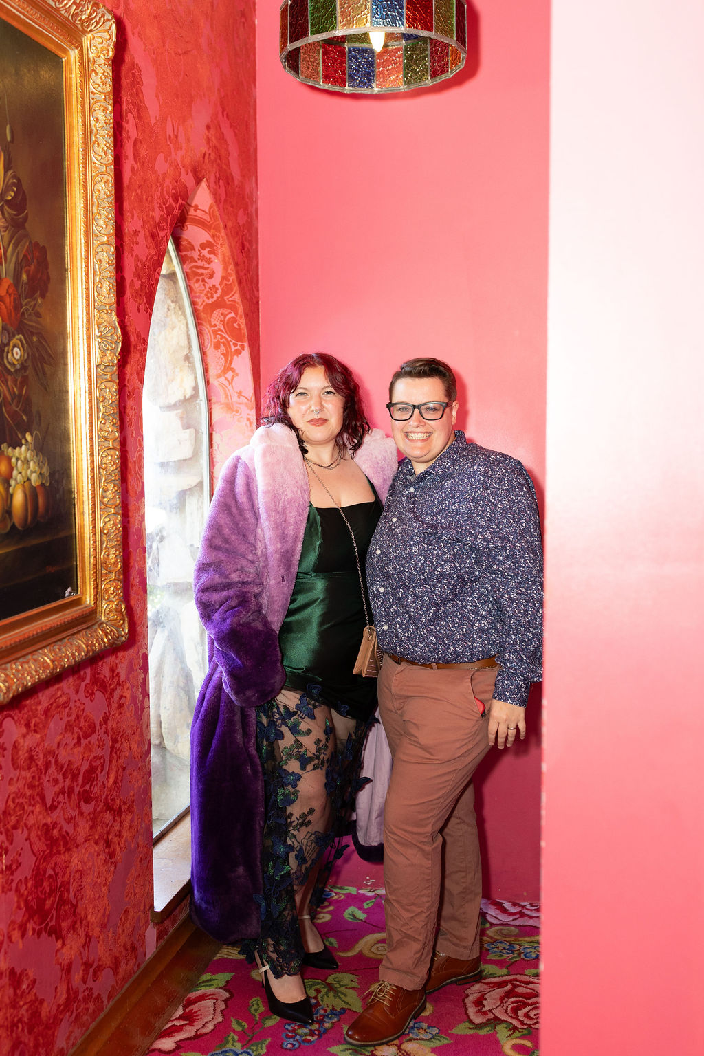 Happy wedding guests smile while standing in a pink hallway