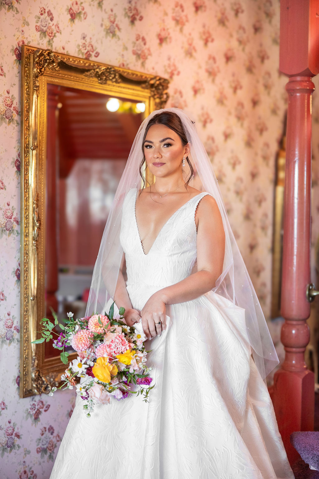 A bride smiles in the Madonna Inn wedding venue bridal suit holding her bouquet