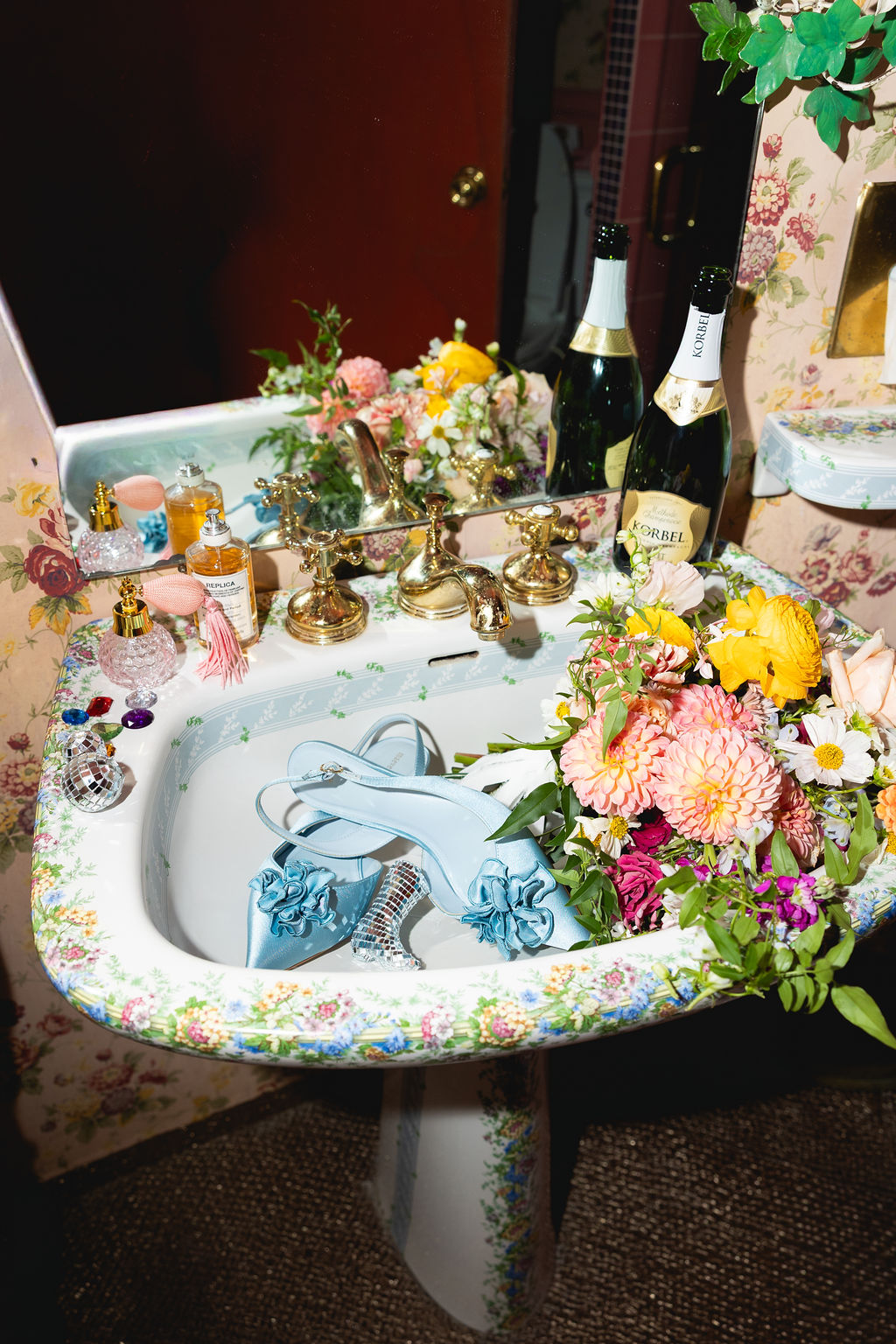 Details of blue wedding shoes in an ornate sink with colorful flowers