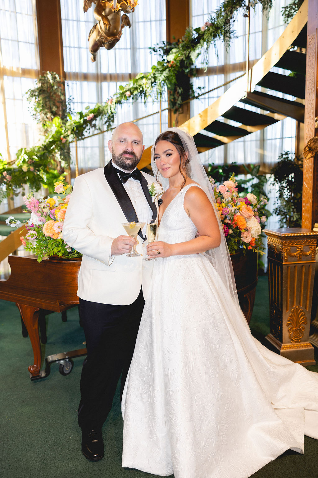 A bride and groom stand toasting cocktails in the grand Madonna Inn wedding venue lobby