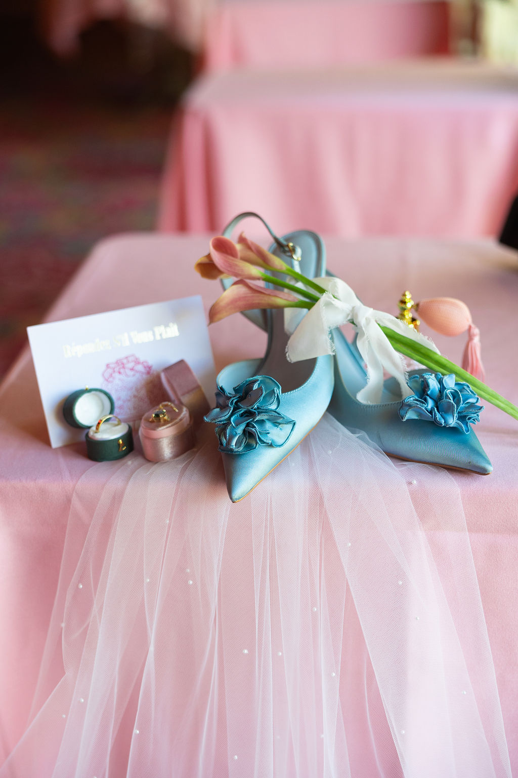 Details of blue bridal shoes and rings on a pink table