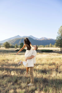 Couple spinning and posing for the engagement photos with a mountain range in the background