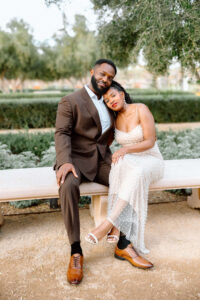 A couple embraces while sitting on a bench while posing for the engagement photos