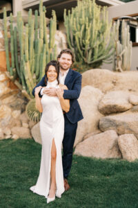 Couple embraces for the engagement portraits surrounded by greenery. They were elegant silk clothing