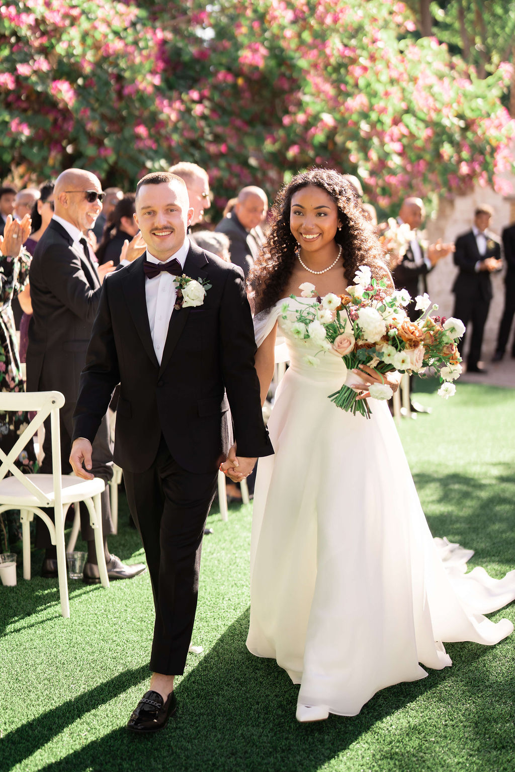 A bride smiles big while walking up the aisle holding the hand of her happy groom after their the scott resort wedding ceremony