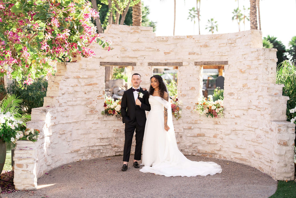 A bride and groom stand in a small garden structure