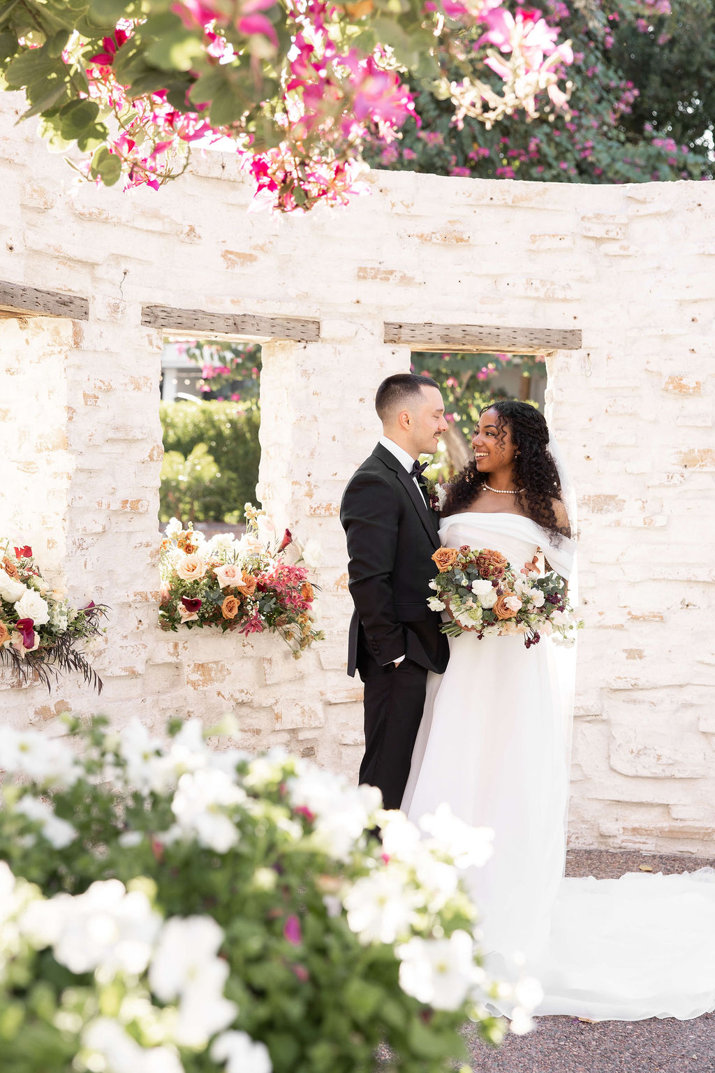 Newlyweds smile at each other while snuggling in a garden patio surrounded by flowers at the scott resort wedding venue