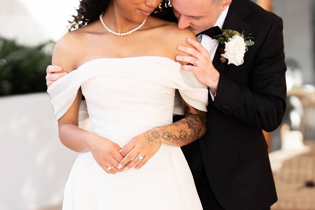 A groom kisses the shoulder of his bride on the patio during their the scott resort wedding